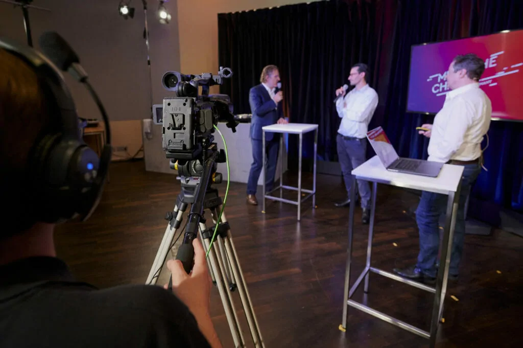 Begrüßung der virtuellen Teilnehmer*innen auf einem hybriden Event in eigens dafür vorgesehenen Studio